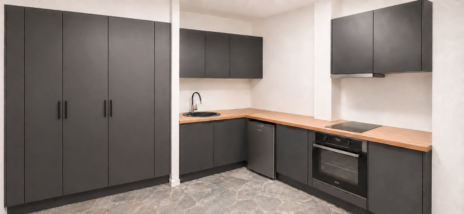 Kitchen and storage area with dark cabinets and stone floor